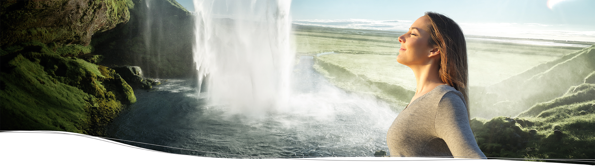 A woman breathes fresh air at the edge of a waterfall.